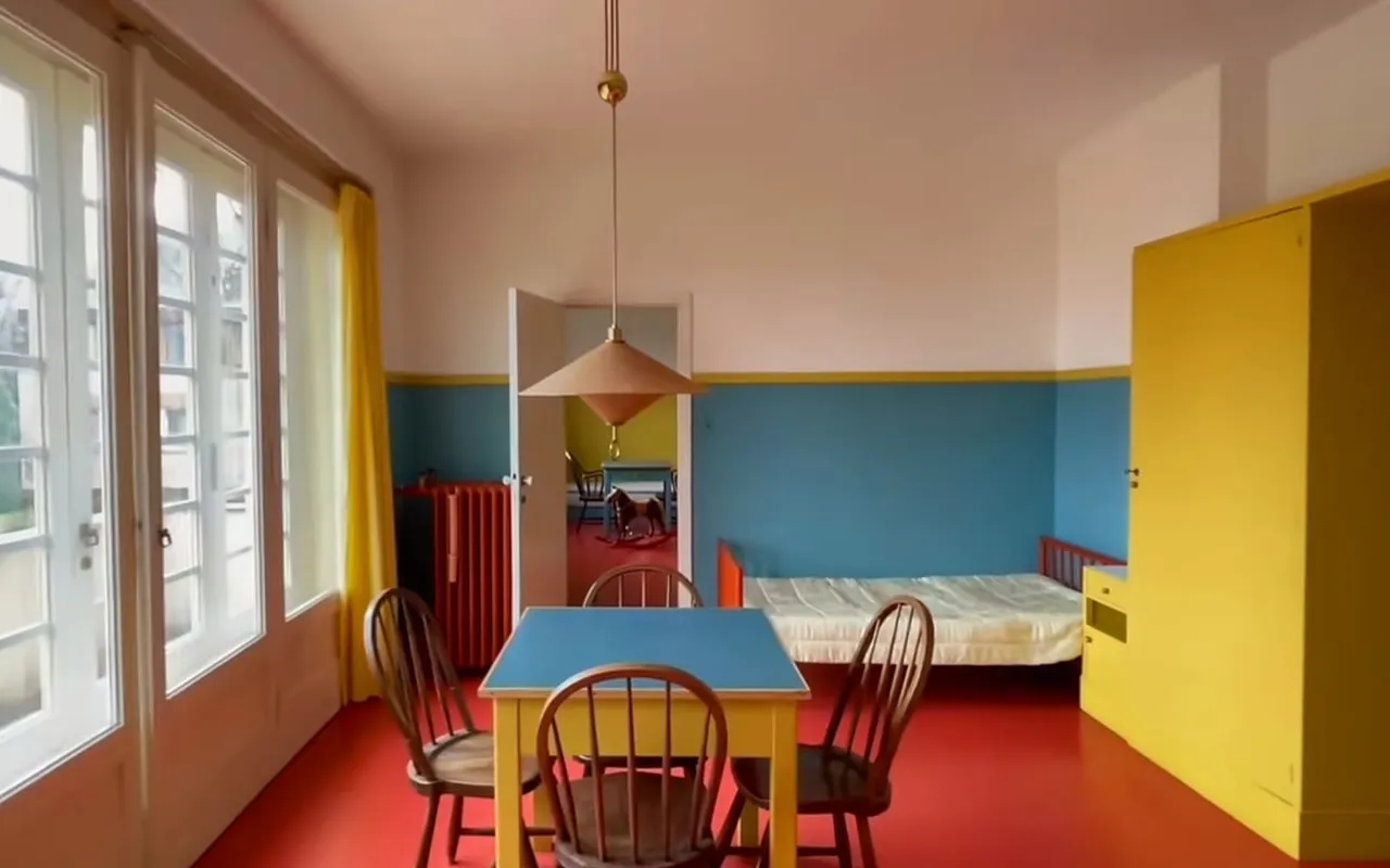 La cameretta dei bambini di Villa Müller con il pavimento rosso, le pareti blu e un armadio giallo