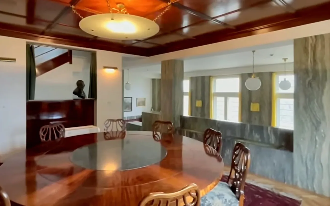 La sala da pranzo di Villa Müller con un tavolo rotondo in mogano e un soffitto in legno a cassettoni